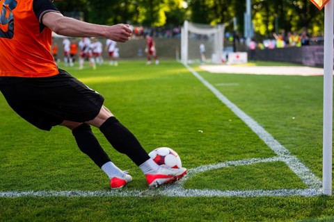A soccer player kicking a ball from the corner line during a professional football match on a
