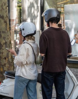 Young couple wearing motorcycle helmets standing next to a Vespa, Frankfurt am Main, Hesse, Germany