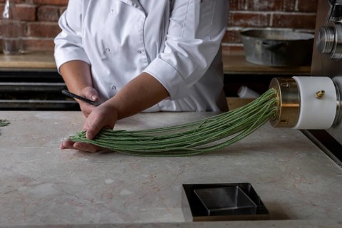 Process of woman preparing handmade pasta. Woman's hands working with dough to make pasta. Chef