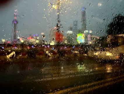 Buildings on the Bund illuminated at night, blurred behind glass in rain, Shanghai, China