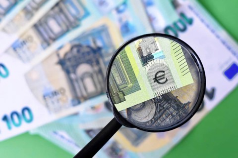 Magnifying glass checking authenticity of euro banknote