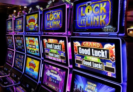 Rows of illuminated slot machines with colorful neon displays on a casino gaming floor, vibrant