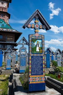 Cemetery with artfully painted tombstones and a traditional wooden church highlighted in the