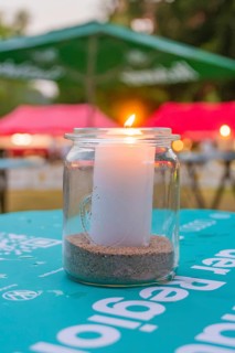 Burning candle in a glass, outside on a table with evening lighting with colorful shades in the