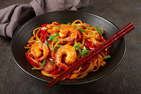 Udon stir-fry shrimp noodles with red bell pepper and green onion, served in a black bowl, with
