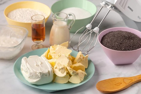 Baking ingredients such as poppy seeds, flour, butter, milk and rum on a work surface