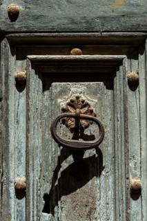 Old rustic metal door knocker on weathered wood