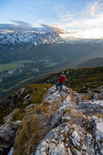 View of Wetterstein mountains with Zugspitze, mountaineer at the summit of Kramerspitz, at sunset,