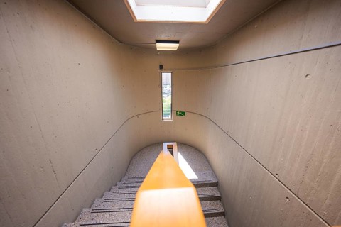 Narrow concrete staircase with skylight and green exit sign, Nagold Hospital of Klinikverbund