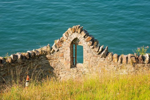 Stone ruin by the sea with a window in a green landscape, Howth, Ireland