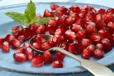Pomegranate seeds and spoons on plate, Punica granatum