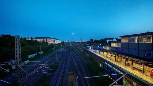 Illuminated track and station zone under an evening sky, view from Bösebrücke, Bornholmer Straße