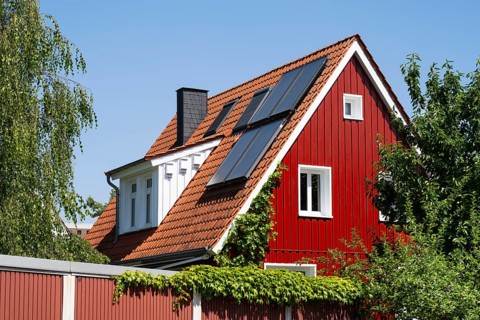 House with pointed gable, photovoltaic on the roof, red wooden façade, sky, Westphalia, North