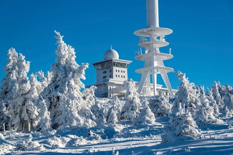 View over snow-covered spruce trees of the telecommunications tower and the radar station on the
