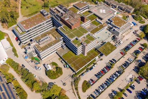 Complex hospital structure with green roofs and numerous parking spaces, taken from the air, Nagold