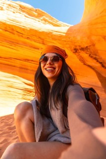 Young woman smiling while taking a selfie, capturing a travel memory inside the vibrant orange