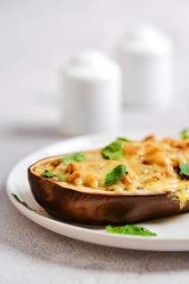 Close-up view of cheesy baked eggplant filled with ground meat topped with melted cheese on white