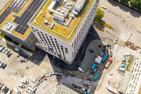 Aerial view of a modern building with green roof and solar panels in an urban environment, new