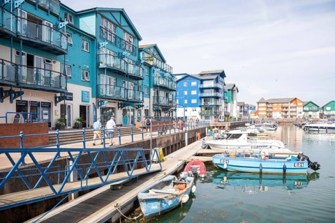 Boats at moorings, modern residential housing development at Exmouth Quay marina, Exmouth, Devon,