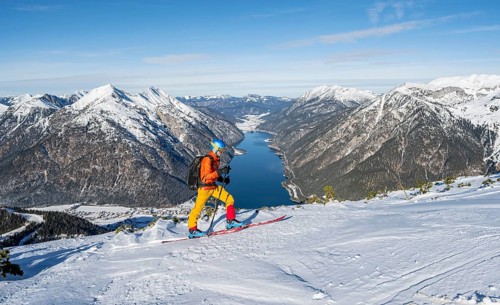 Picturesque view of Achensee and wintry mountain scenery, ski tourers at the summit of Bärenkopf,