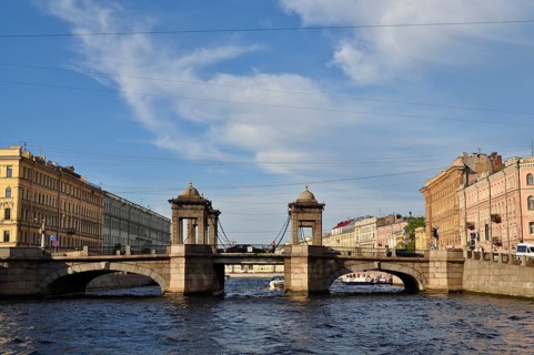 Architecturally distinctive bridge across river with city buildings, Lomonosov Bridge, Saint