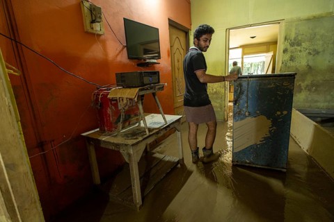 Resident walks around inside his mud-filled and flood-damaged home after floodwaters receded on