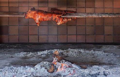Whole suckling pig traditionally grilled on a skewer over an open wood fire, Majorca, Balearic