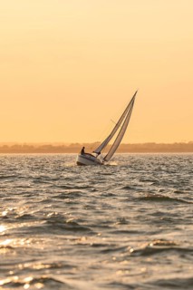 A sailboat at a gentle sunset, golden sky and calm sea, Howth, Ireland