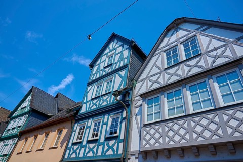 Half-timbered houses with colorful facades and visible cables against a clear sky, Eltville am