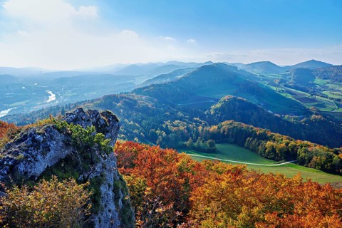 View of an autumnal forest from the Gisliflue, behind the Jura foothills with Wasserfluh and