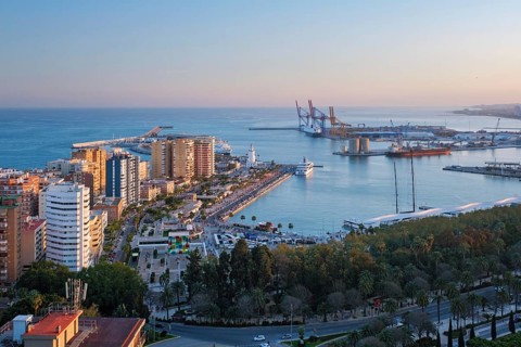Elevated golden hour view of Muelle Uno and the Port of Malaga in Spain, with La Farola lighthouse,