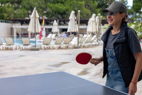 A middle aged beautiful woman focused on a ping pong game at a hotel poolside in Turkiye,