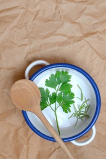 Parsley and rosemary with cooking spoon on pot