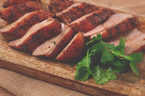 Roast duck breast, sliced, on a wooden chopping board, close-up, no people