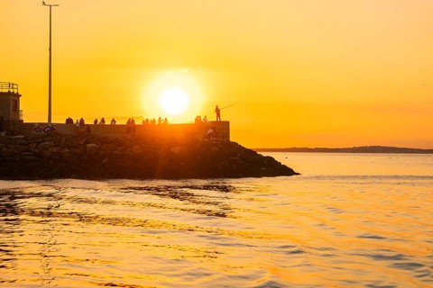 People on a pier in sunset light, fishing on the horizon, Howth, Ireland