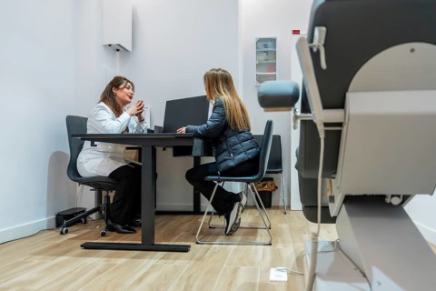 Female doctor in a professional white coat discussing treatment options with a young woman, sitting