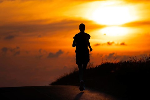 A female jogger runs along a Feldberg near Frankfurt am Main in the morning just after sunrise,