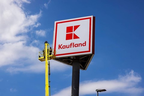 Advertising pylon at the Kaufland supermarket. Workers are renewing the logo by means of a climber.