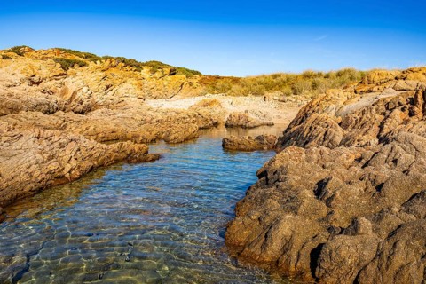 Landscape of the coastline with blue water at Marinedda Coast on a sunny day, Sardinia, Italy