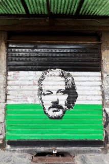 Portrait of whistleblower Julian Assange, stencil painting on a shutter, street art, historic old