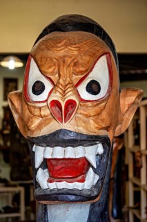 Expressive, colorful mask sculpture with big eyes and open mouth, artisan leg carving masks in