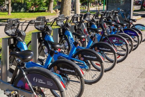 Parked electric and standard Bixi ride sharing bikes with company sponsor logos on rear wheel