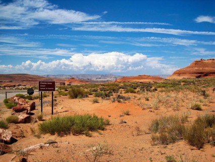 Barren desert landscape and typical red sandstone formations, Lake Powell on the horizon, hiking in