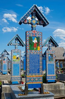 Artistically carved tomb with folklore motifs under blue sky, traditional wooden grave sites, Happy