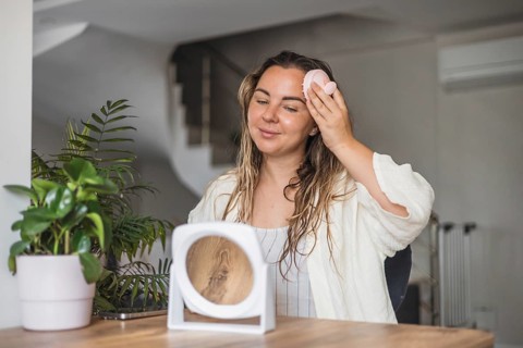 Woman, aking sculp head massage and applying hair product while looking in a mirror in a modern