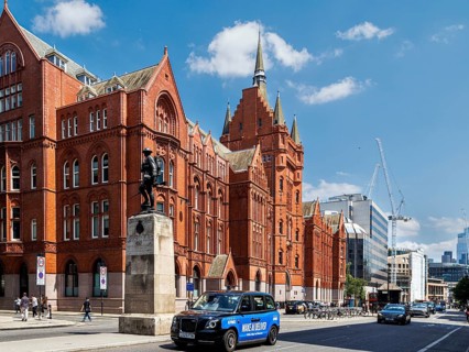 A black cab passes the red terracotta Holborn Bars, Alfred Waterhouse's Gothic Revival former