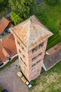 Close-up of a historic tower with red tiled roof, surrounded by other buildings, Calwer