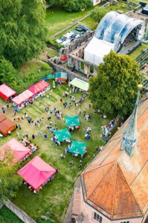 Summer festival from above with colorful tents, a stage and a crowd in daylight, Calwer