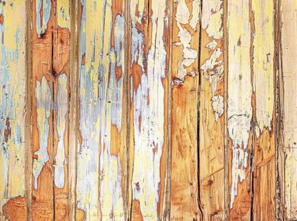 Abstract close-up of weathered wooden wall with peeling yellow, white, blue and orange paint
