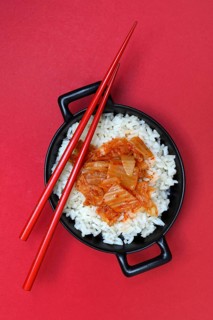 Kimchi, fermented vegetables on rice in bowl with chopsticks